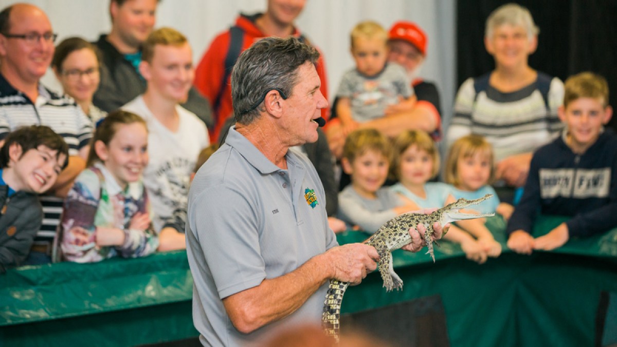 Guy holding a small reptile in a show