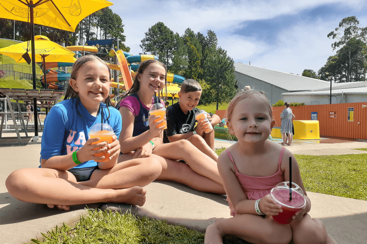Vivienne Jolie-Pitt et al. sitting on a bench holding an umbrella