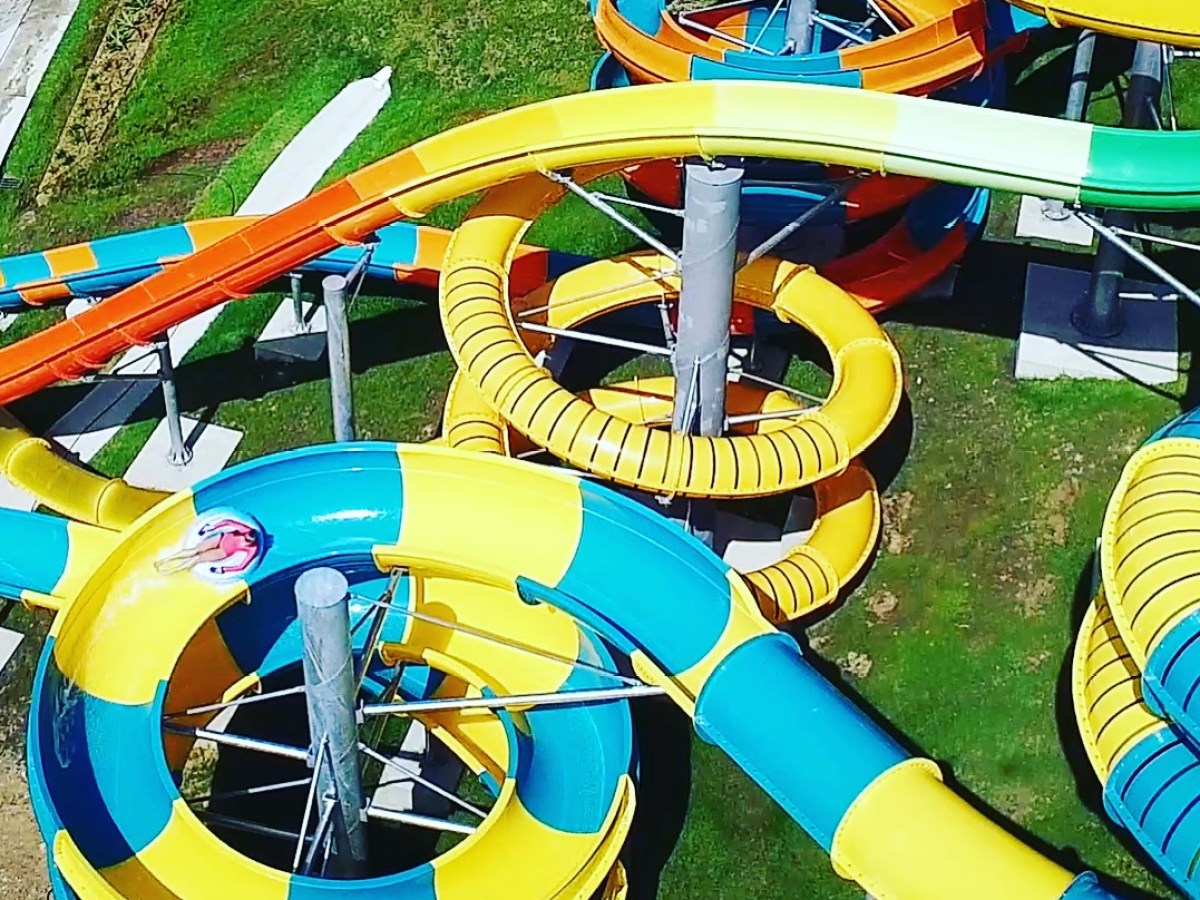 Spiral water slide with bright yellow, blue, and orange sections in a water park.