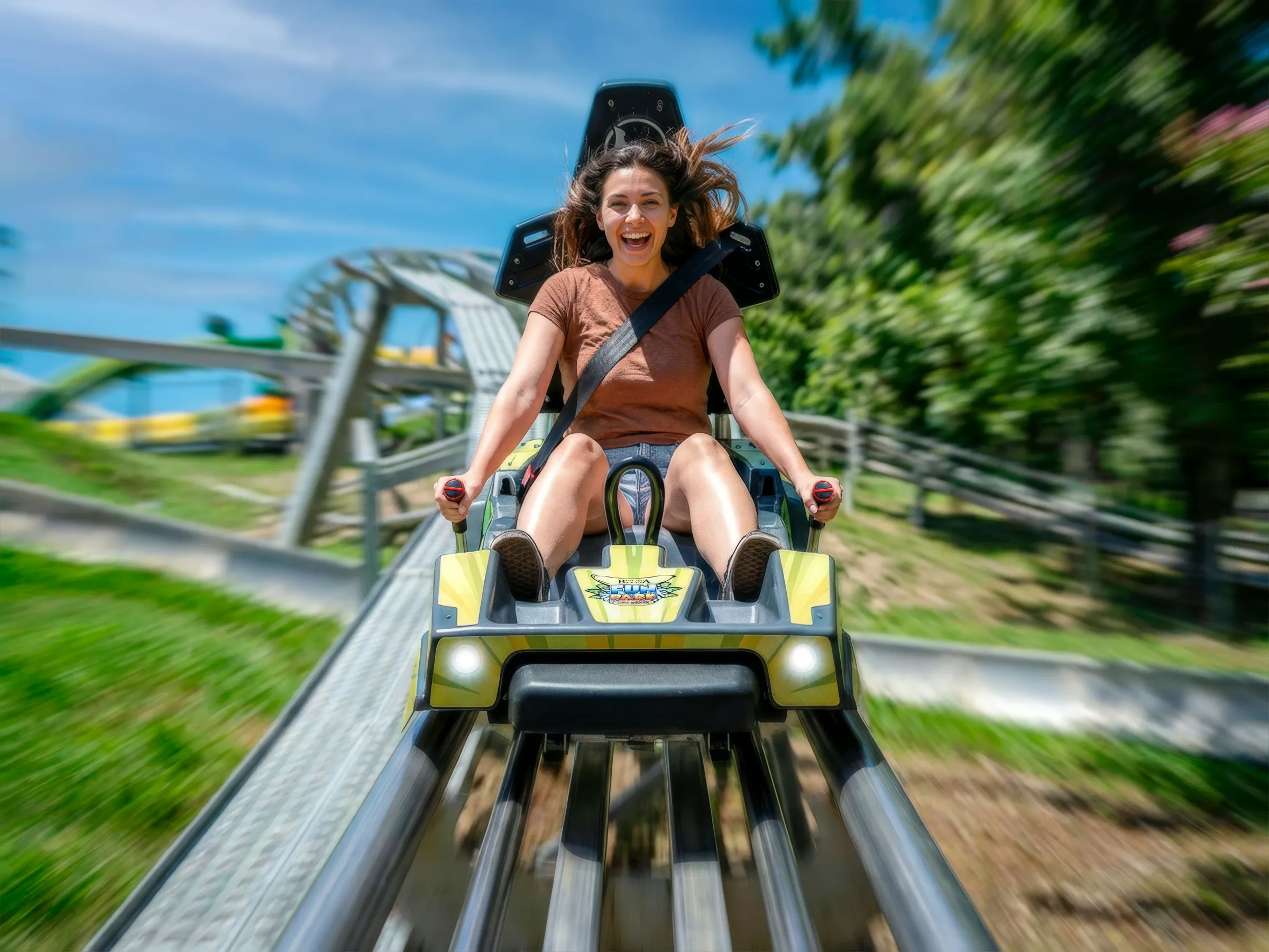 Woman joyfully riding a roller coaster, holding controls with blurred background.