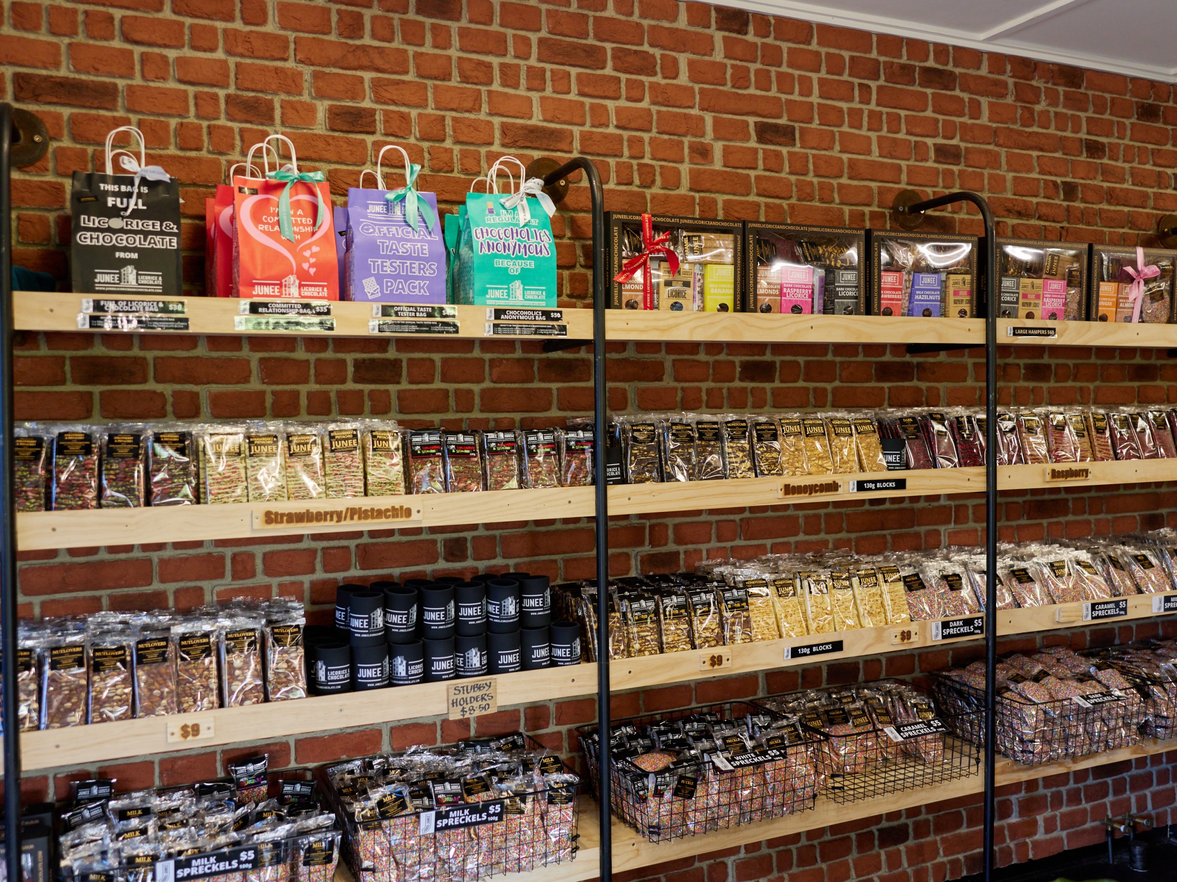 Shelves with assorted packaged snacks against a brick wall in a store.