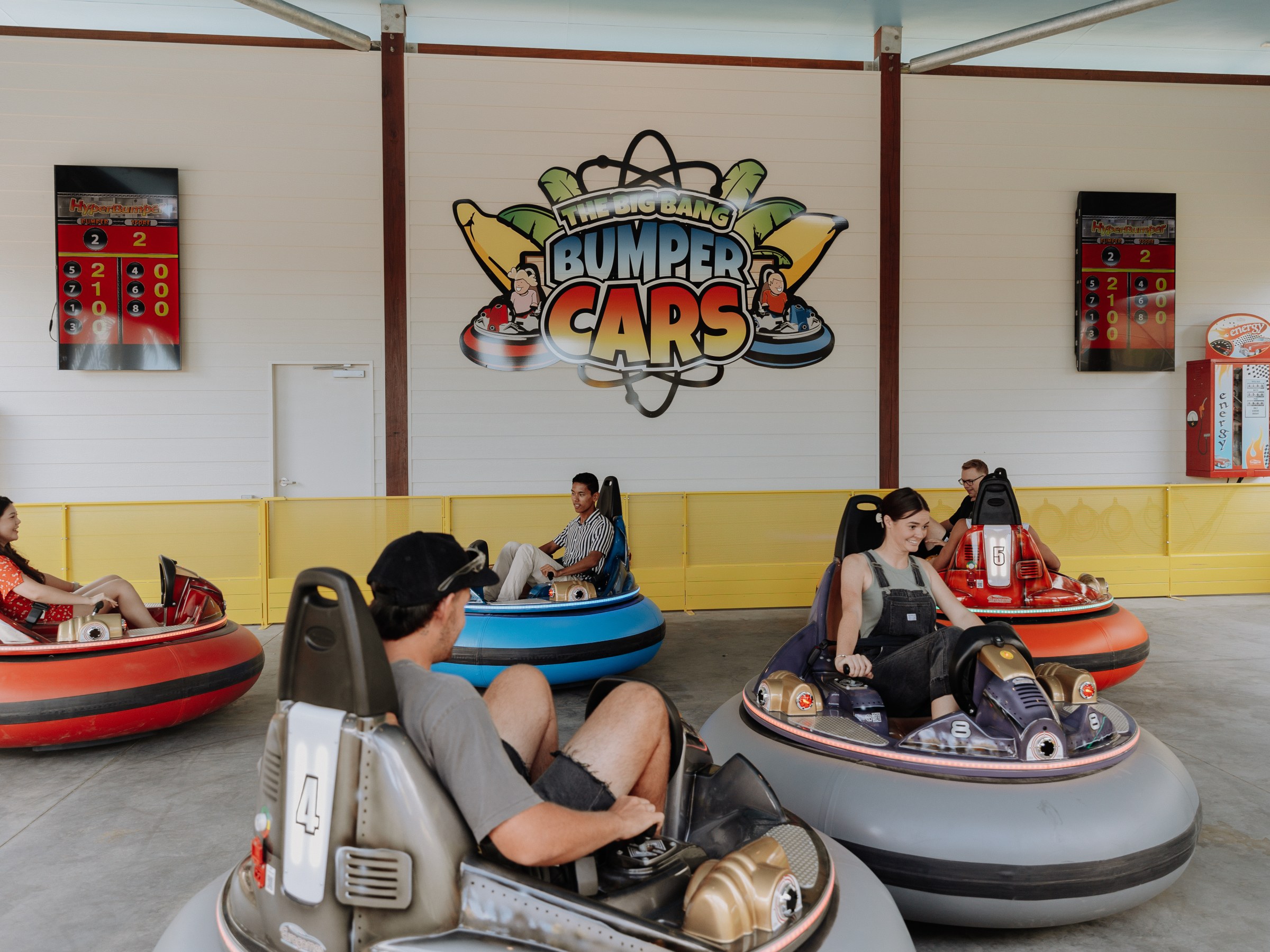 People riding bumper cars in an indoor amusement park setting.