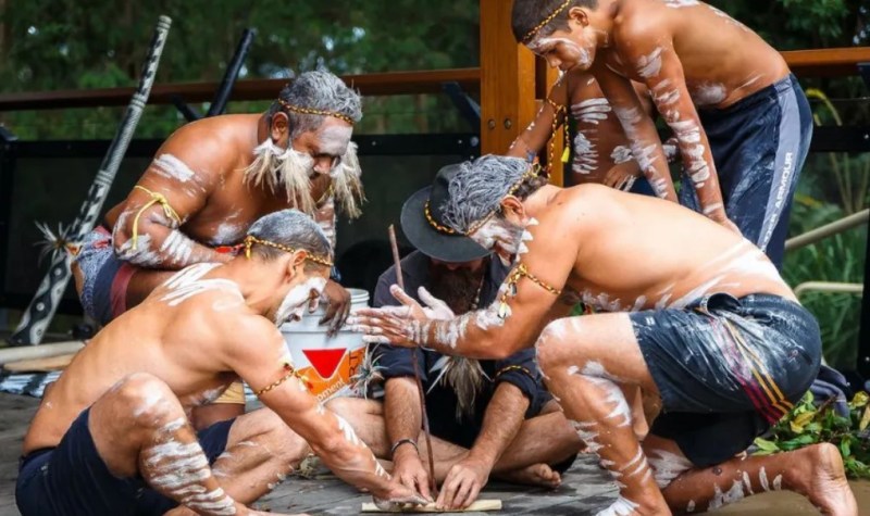 Group of Indigenous men with body paint performing a cultural ceremony.