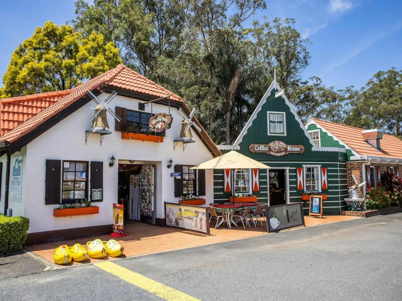 Two charming Dutch-style buildings with outdoor seating and trees in the background.