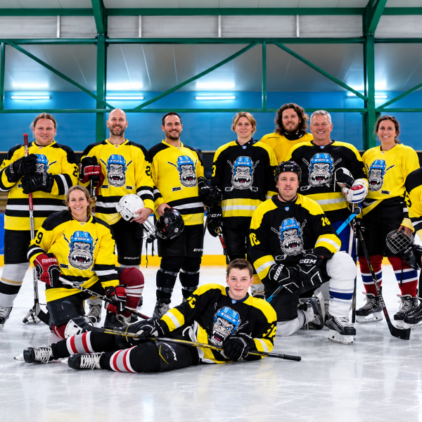 Group of hockey players in yellow jerseys posing on ice rink.
