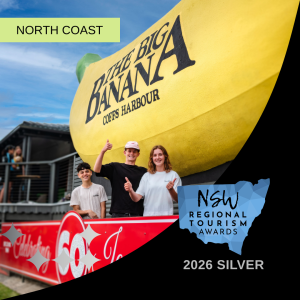 Three people in front of the Big Banana with a 2026 Silver tourism award banner.